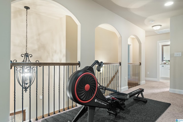 exercise room with carpet floors and an inviting chandelier