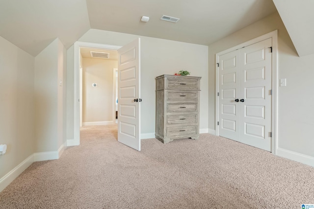 unfurnished bedroom with a closet, light colored carpet, and vaulted ceiling