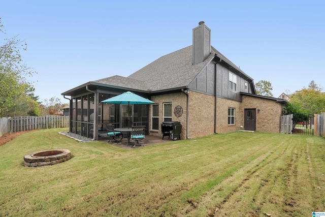 rear view of house featuring a sunroom, a yard, and a fire pit