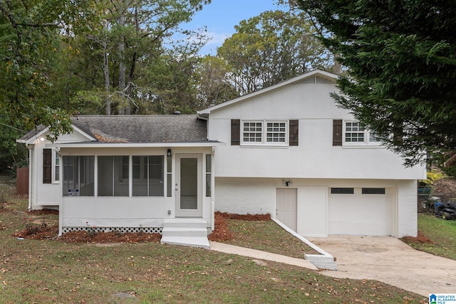 tri-level home featuring a sunroom, a garage, and a front lawn