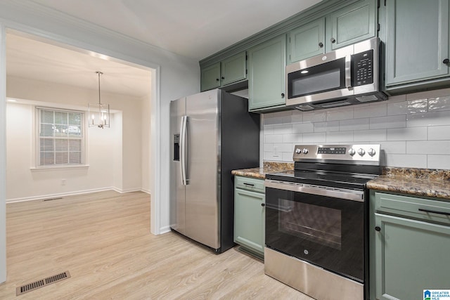 kitchen featuring backsplash, green cabinets, hanging light fixtures, light wood-type flooring, and stainless steel appliances