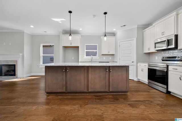 kitchen with pendant lighting, a center island, white cabinets, dark hardwood / wood-style floors, and appliances with stainless steel finishes