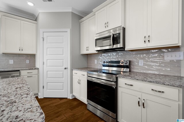 kitchen with dark wood-type flooring, white cabinets, decorative backsplash, light stone countertops, and stainless steel appliances