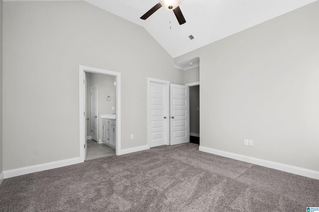 unfurnished bedroom with ceiling fan, carpet floors, high vaulted ceiling, and ensuite bath