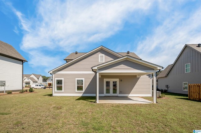 rear view of property featuring a lawn, a patio area, and french doors