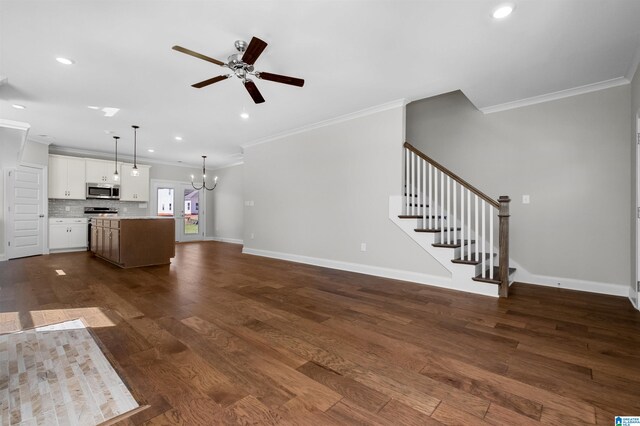 unfurnished living room featuring ceiling fan with notable chandelier, dark hardwood / wood-style floors, and crown molding