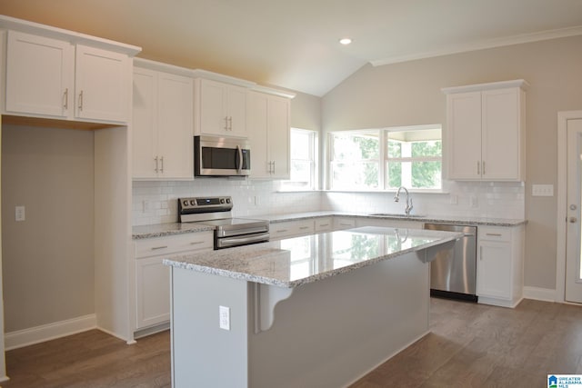 kitchen with tasteful backsplash, white cabinets, a kitchen island, and stainless steel appliances