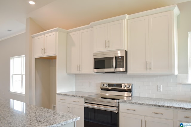 kitchen featuring backsplash, white cabinetry, light stone countertops, and stainless steel appliances