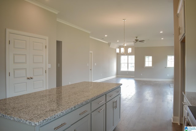 kitchen with pendant lighting, a center island, hardwood / wood-style flooring, ceiling fan, and ornamental molding