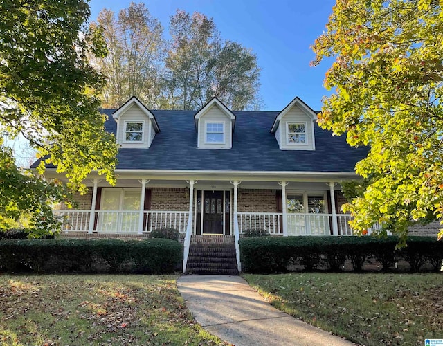 cape cod-style house featuring covered porch and a front lawn