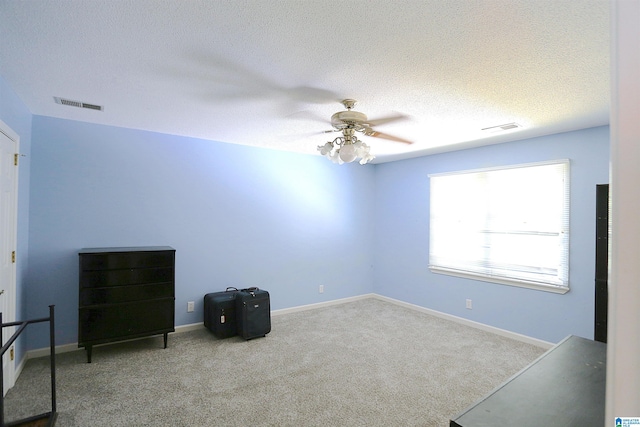 unfurnished bedroom featuring ceiling fan, light colored carpet, and a textured ceiling