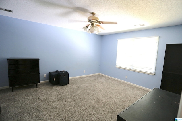 carpeted empty room with ceiling fan and a textured ceiling