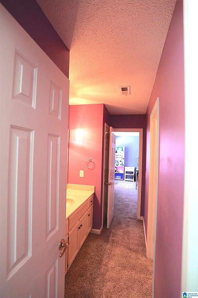 hall featuring dark carpet and a textured ceiling