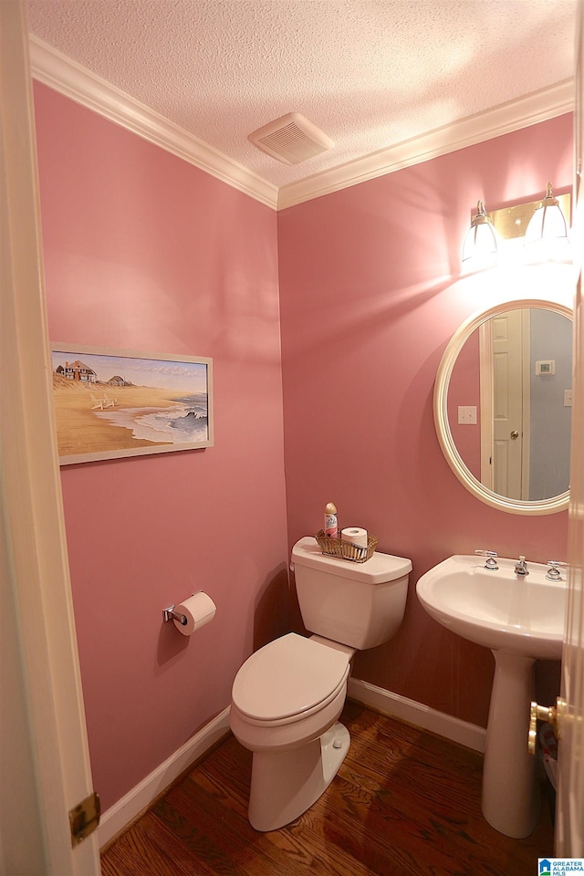 bathroom with toilet, hardwood / wood-style floors, a textured ceiling, and ornamental molding