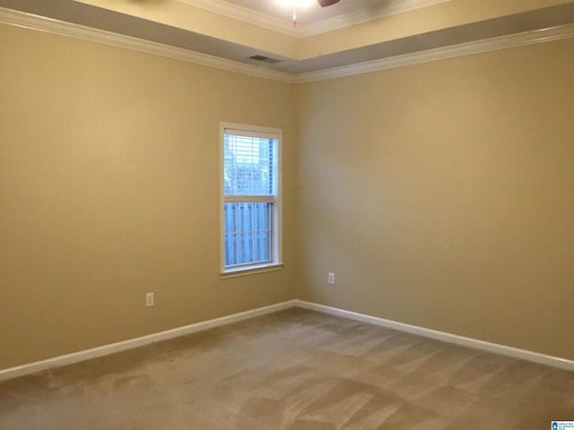 carpeted empty room featuring a tray ceiling, ceiling fan, and crown molding