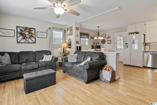 living room featuring ceiling fan with notable chandelier and light hardwood / wood-style flooring