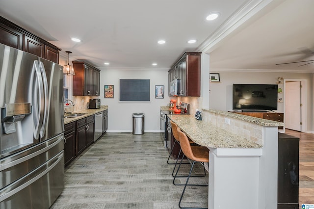 kitchen with hanging light fixtures, decorative backsplash, appliances with stainless steel finishes, kitchen peninsula, and a breakfast bar area