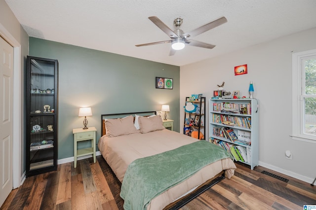 bedroom with a textured ceiling, ceiling fan, and dark wood-type flooring