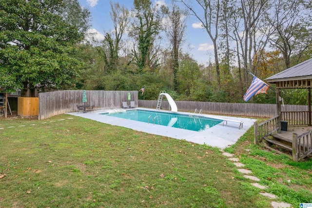 view of swimming pool featuring a diving board, a lawn, and a water slide