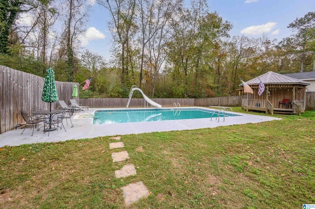 view of swimming pool featuring a patio area, a diving board, a yard, and a water slide