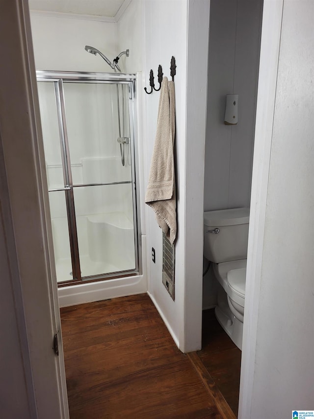 bathroom with toilet, an enclosed shower, and hardwood / wood-style flooring