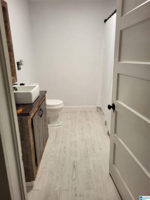 bathroom with toilet, vanity, and hardwood / wood-style flooring