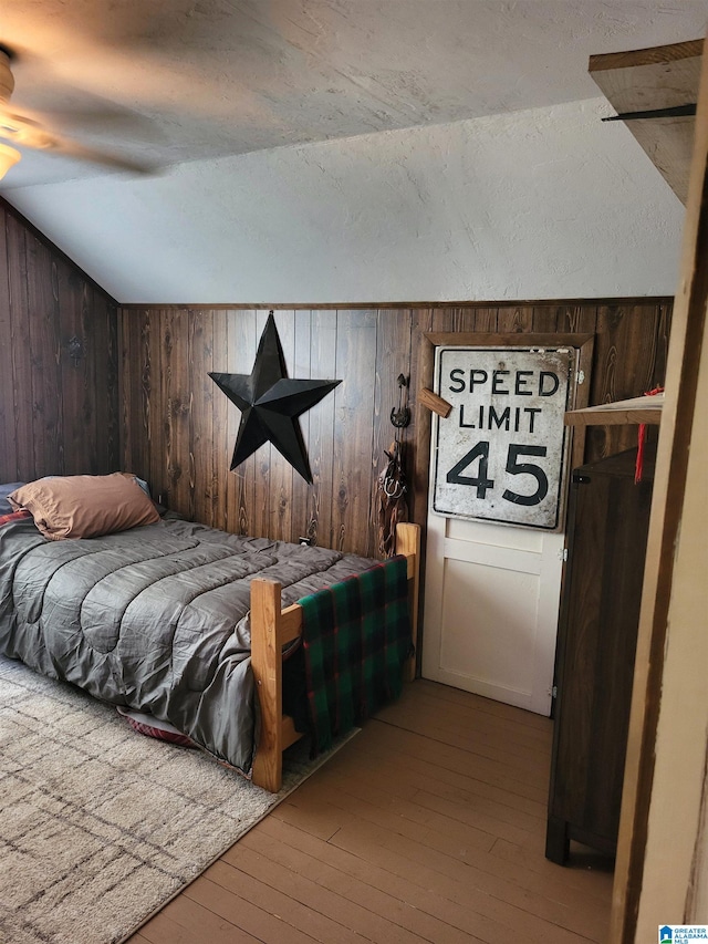 bedroom featuring ceiling fan, wood walls, and wood-type flooring