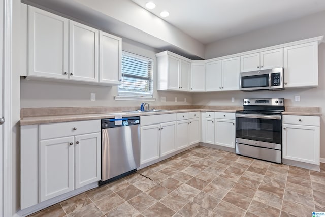 kitchen featuring stainless steel appliances, white cabinetry, and sink