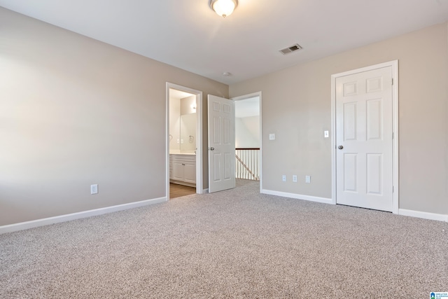 unfurnished bedroom with connected bathroom and light carpet