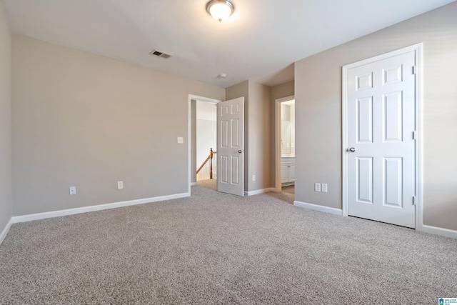 unfurnished bedroom featuring ensuite bathroom and light colored carpet