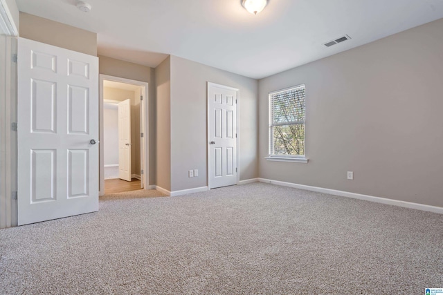 unfurnished bedroom with light colored carpet and a closet