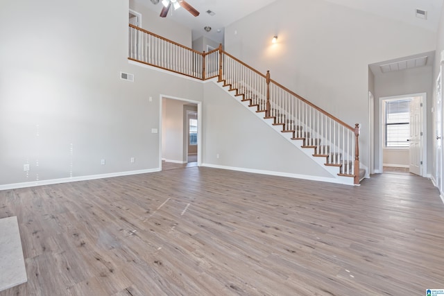 unfurnished living room featuring light wood-type flooring, high vaulted ceiling, and ceiling fan