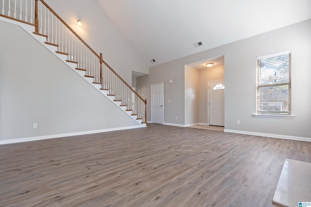 unfurnished living room with high vaulted ceiling and wood-type flooring