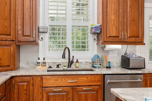 kitchen featuring light stone countertops, stainless steel dishwasher, and sink