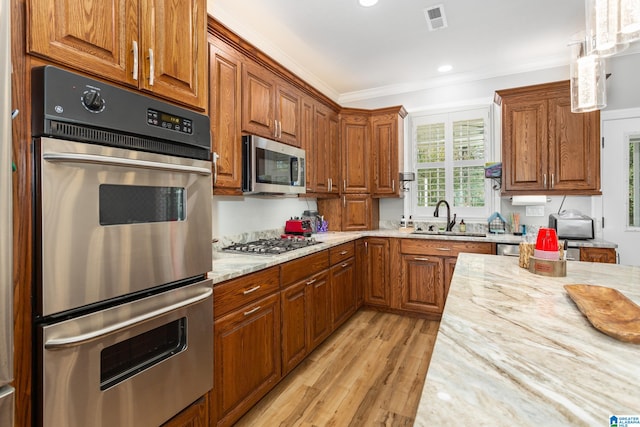 kitchen featuring sink, stainless steel appliances, light stone counters, crown molding, and light wood-type flooring