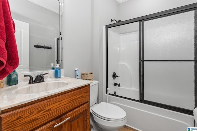 full bathroom featuring vanity, bath / shower combo with glass door, and toilet