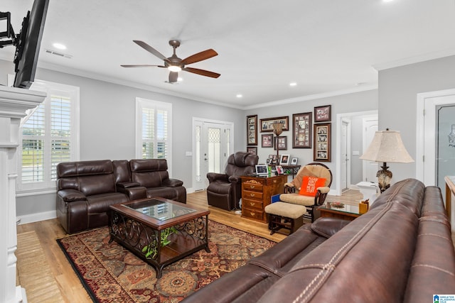 living room featuring ceiling fan, light wood-type flooring, crown molding, and a wealth of natural light