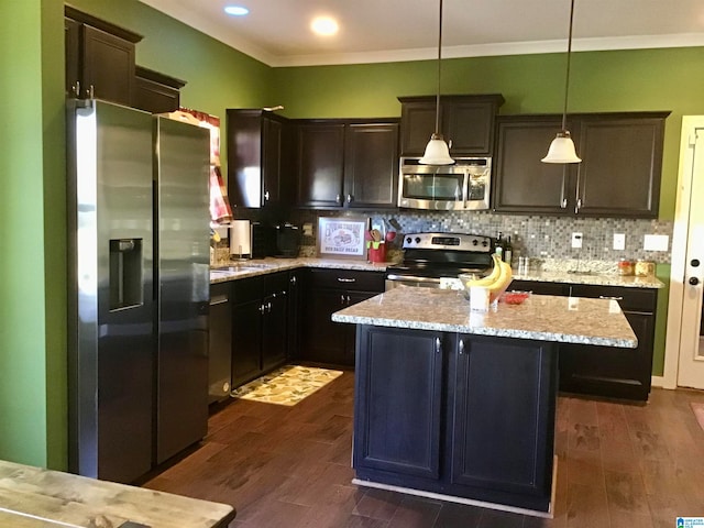 kitchen with appliances with stainless steel finishes, dark hardwood / wood-style flooring, decorative light fixtures, and a kitchen island