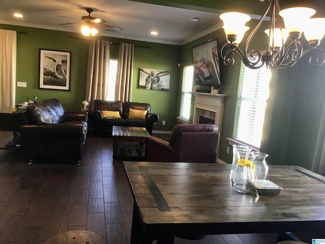 dining space with ceiling fan with notable chandelier, crown molding, and dark wood-type flooring