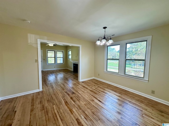 interior space with ceiling fan with notable chandelier, light hardwood / wood-style floors, and a wealth of natural light