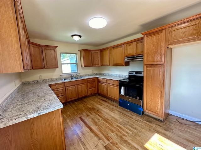 kitchen featuring sink, black electric range, light stone counters, and light wood-type flooring