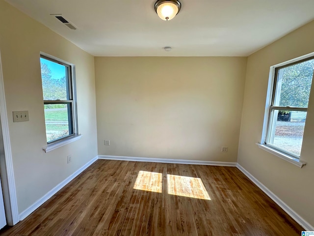 empty room with a healthy amount of sunlight and dark hardwood / wood-style floors