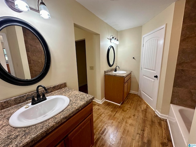 bathroom with a tub to relax in, vanity, and wood-type flooring