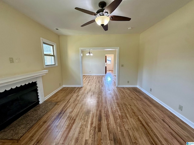 unfurnished living room featuring light hardwood / wood-style floors and ceiling fan with notable chandelier