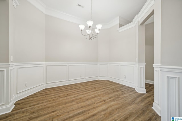 empty room with a chandelier, crown molding, and dark wood-type flooring