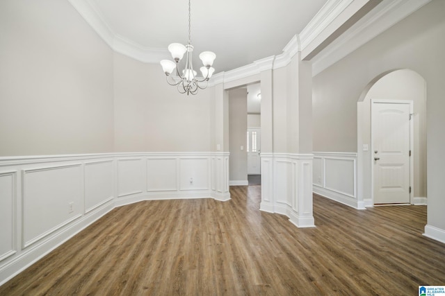 unfurnished dining area with hardwood / wood-style flooring, crown molding, and an inviting chandelier