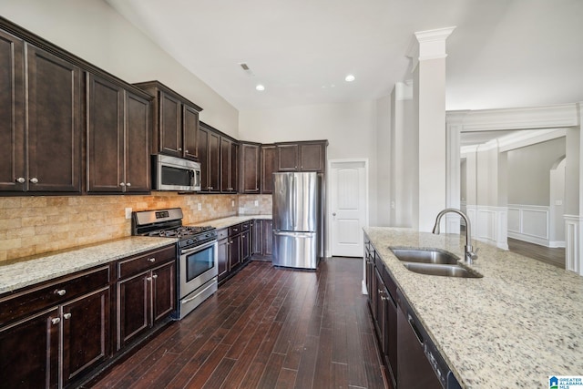 kitchen featuring dark brown cabinetry, light stone countertops, sink, stainless steel appliances, and dark hardwood / wood-style flooring