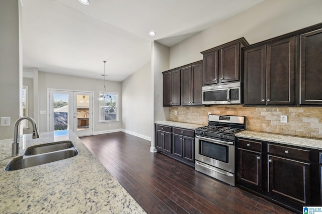 kitchen with dark hardwood / wood-style flooring, light stone counters, stainless steel appliances, sink, and hanging light fixtures