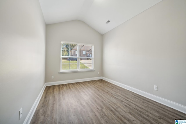 empty room with hardwood / wood-style floors and vaulted ceiling