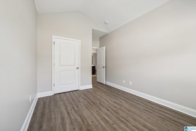 unfurnished bedroom featuring lofted ceiling and dark wood-type flooring